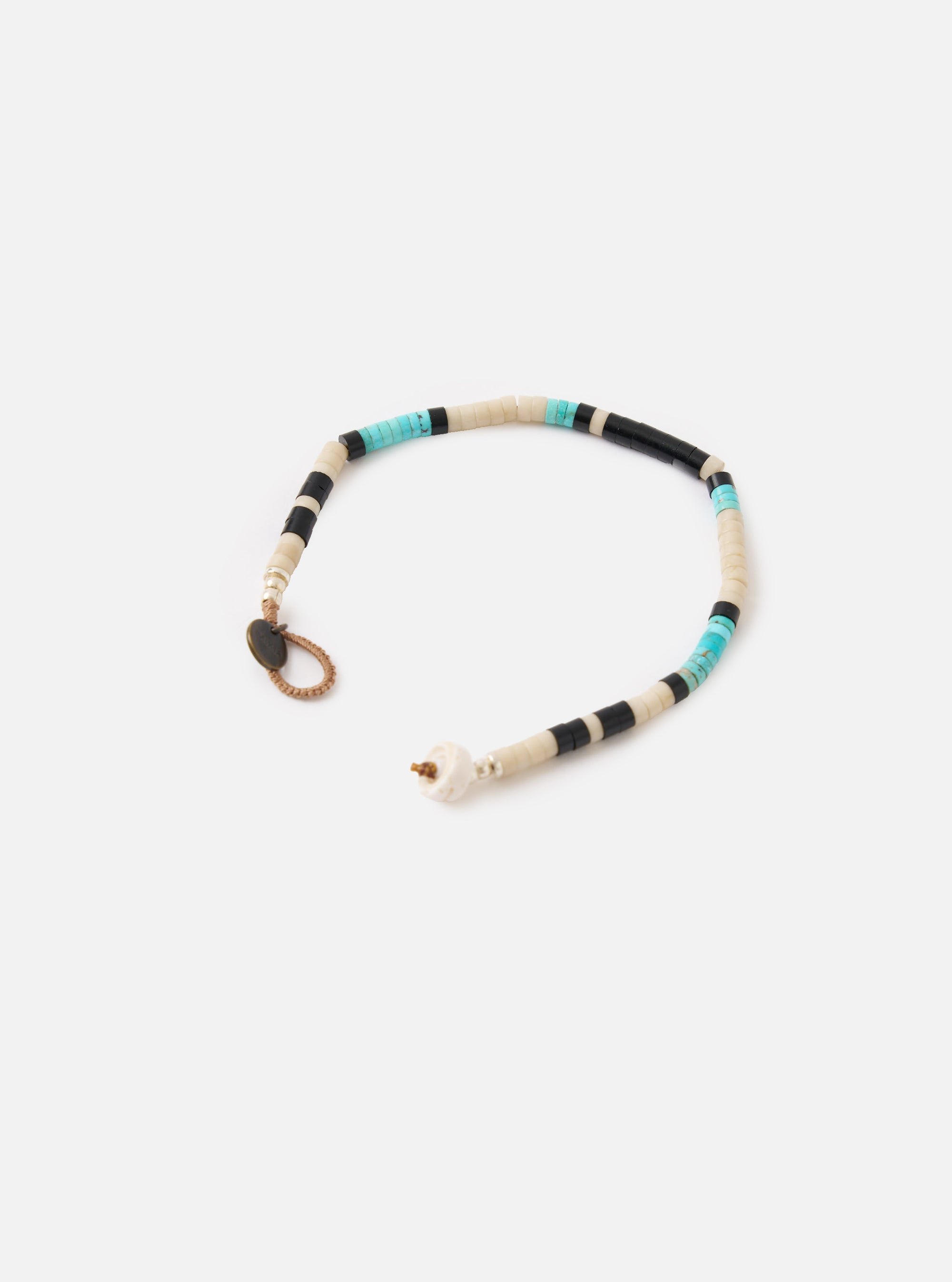 Mikia Fossil Jasper/Turquoise Heishi Beads Bracelet on a white background. The bracelet features turquoise, black, and cream beads. The bracelet has a brown cord and a metal clasp.