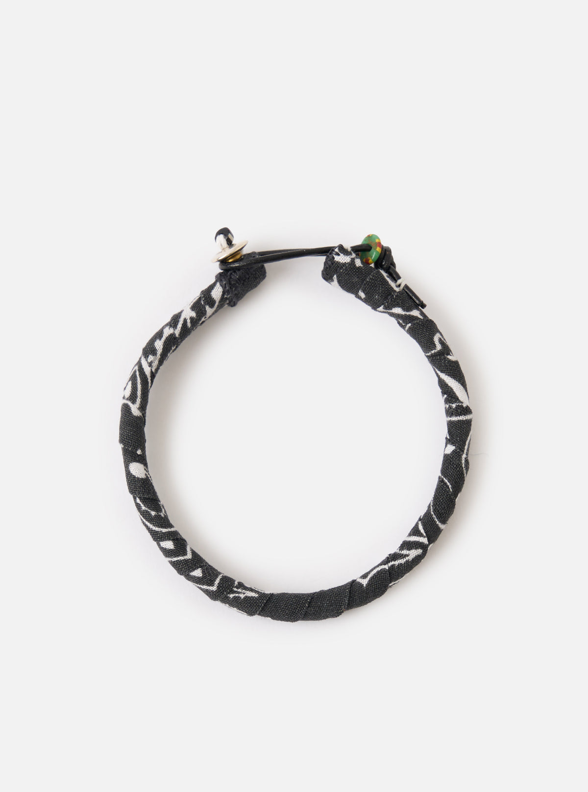 A close up image of the Mikia Black Bandana Bracelet on a white background. The bracelet is black with patches of white.