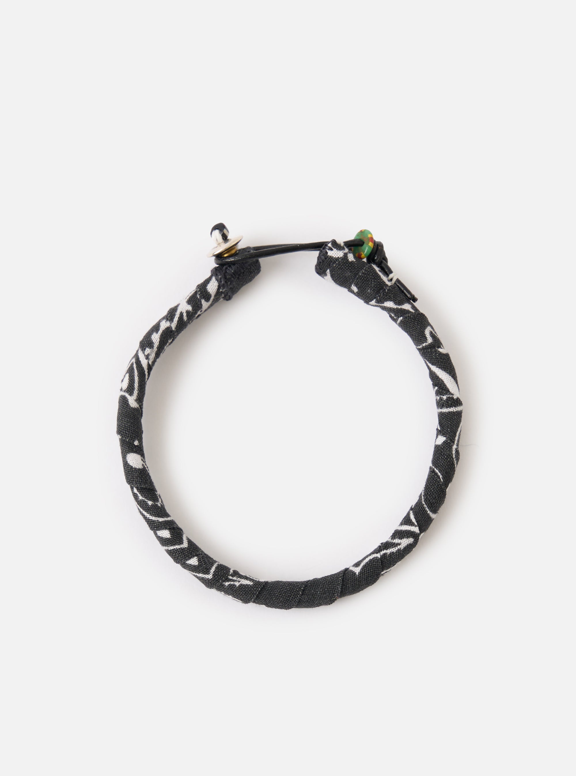 A close up image of the Mikia Black Bandana Bracelet on a white background. The bracelet is black with patches of white.