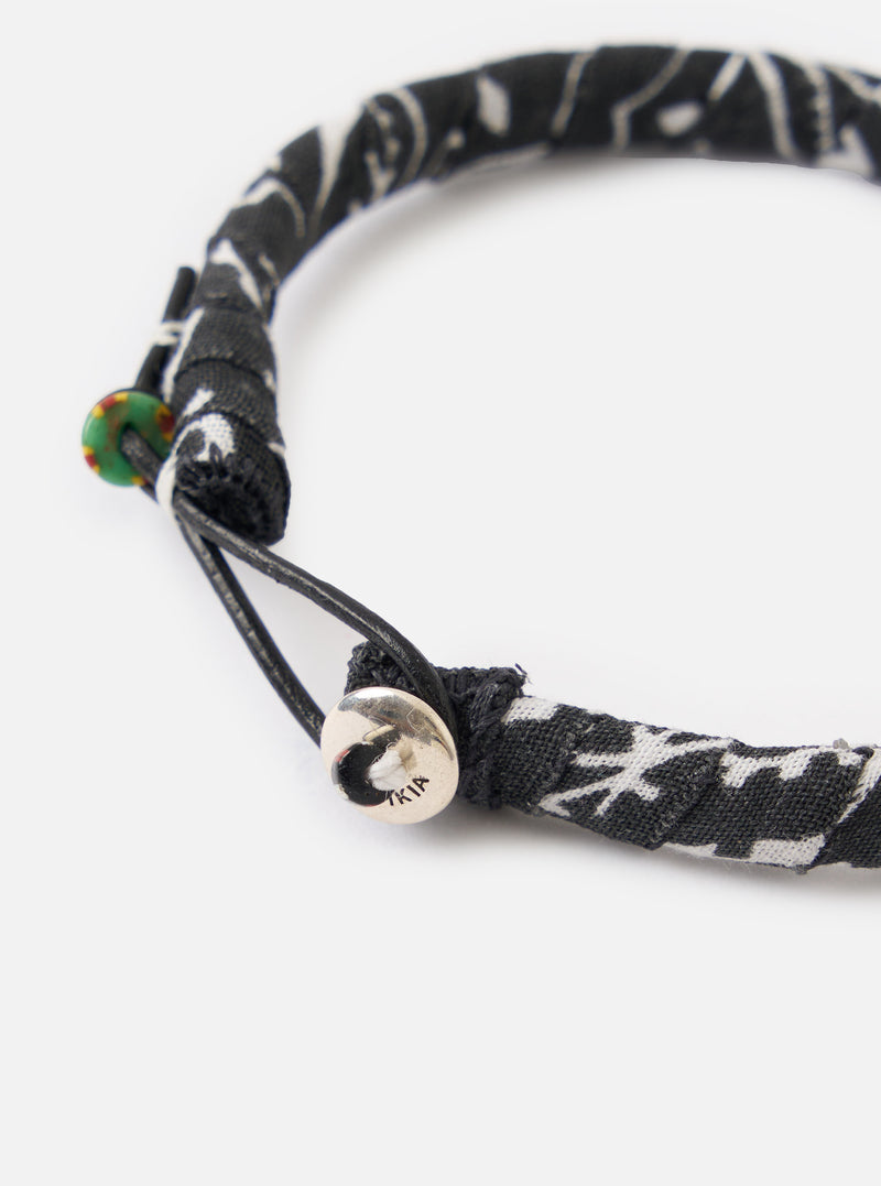 Close-up of the Mikia Black Bandana Bracelet on a white background. The bracelet features a black and white patterned fabric and a silver button closure.