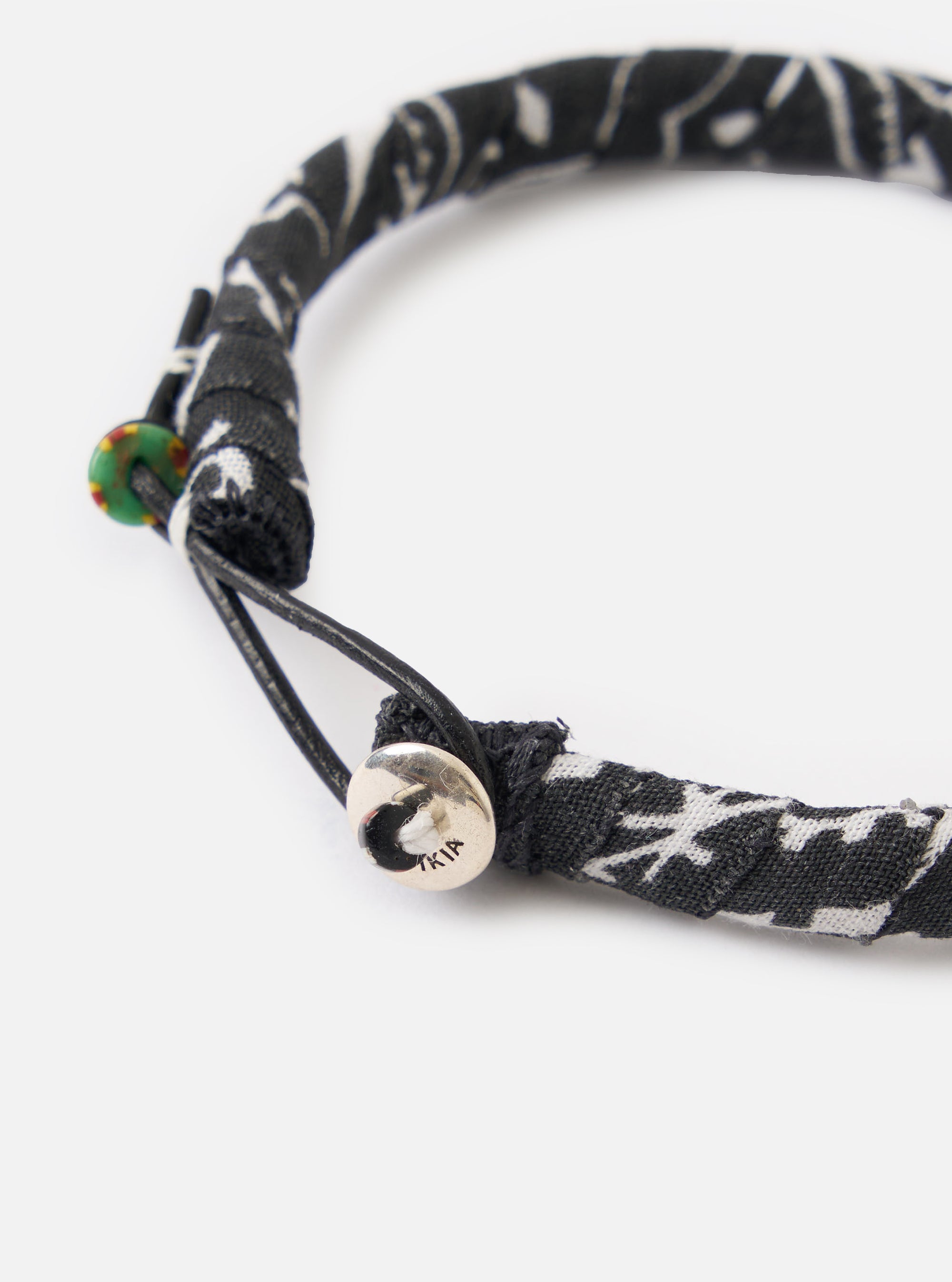 Close-up of the Mikia Black Bandana Bracelet on a white background. The bracelet features a black and white patterned fabric and a silver button closure.