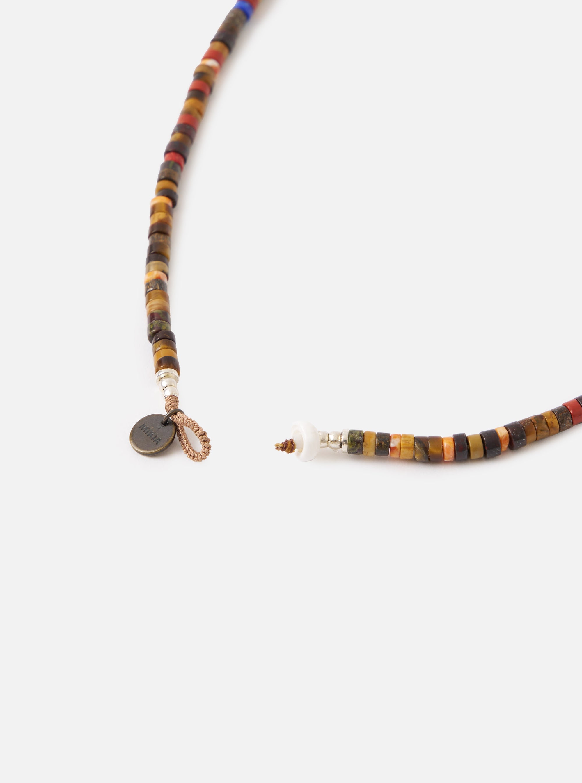 Close-up of the Mikia Brown Multi Heishi Beads Necklace on a white surface. The necklace features brown, red, and orange beads. The clasp is visible.