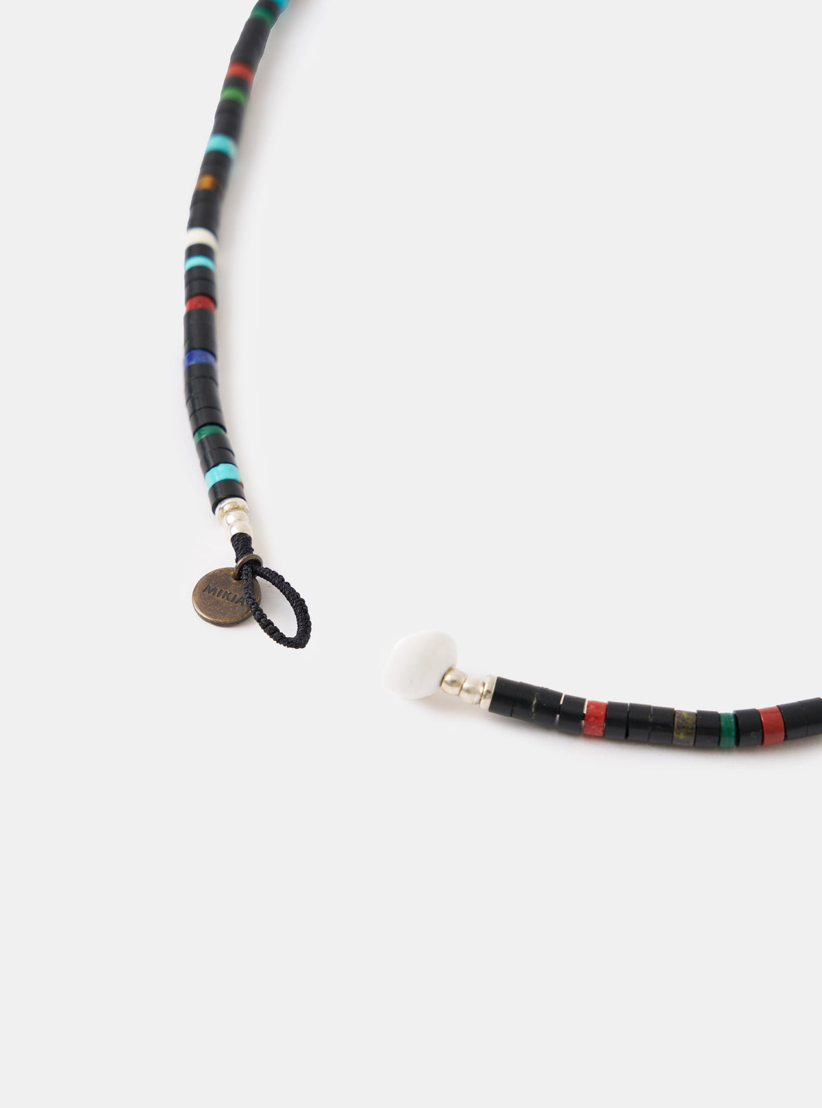 Close-up of the Mikia Jet Multi Heishi Beads Necklace on a white background. The necklace features black, red, green, and blue beads. The clasp is open, showing a white bead.