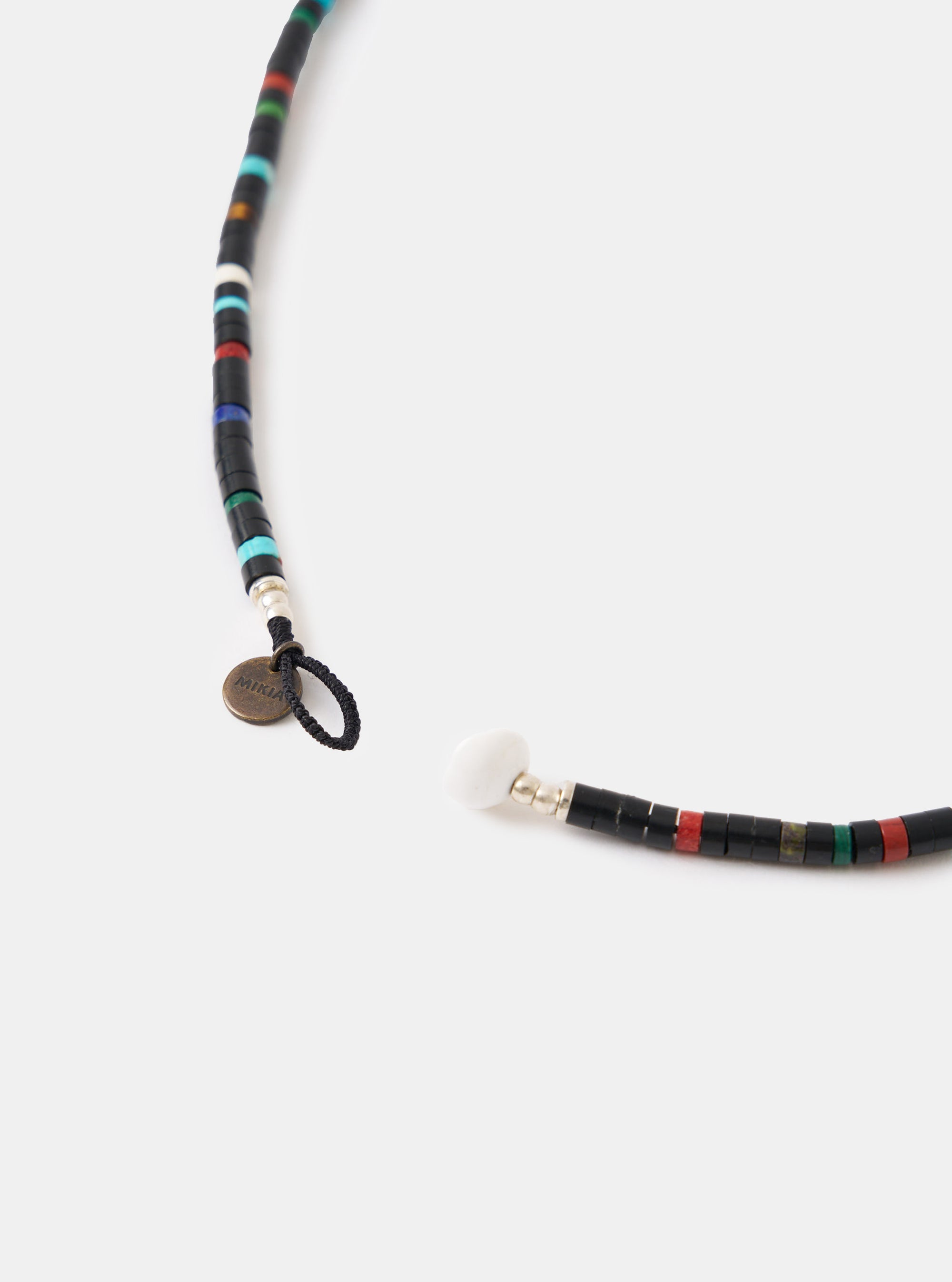Close-up of the Mikia Jet Multi Heishi Beads Necklace on a white background. The necklace features black, red, green, and blue beads. The clasp is open, showing a white bead.