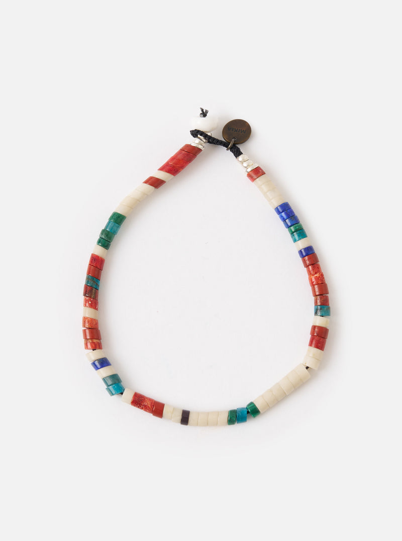 The Mikia Safari Heishi Beads Bracelet on a white surface. The bracelet features red, white, blue, and green beads. 