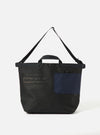 master-piece x Universal Works Black Recycled Tech Canvas Large Tote Bag on a white background. The bag is black with a navy pocket. It has black handles and a shoulder strap.