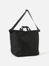 The master-piece x Universal Works Black Recycled Tech Canvas Large Tote Bag. Black tech canvas with handles and shoulder strap. Shot on a white background.