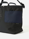 Close-up of the master-piece x Universal Works Black Recycled Tech Canvas Large Tote Bag. Features black canvas with a navy pocket. Shot on a white background.