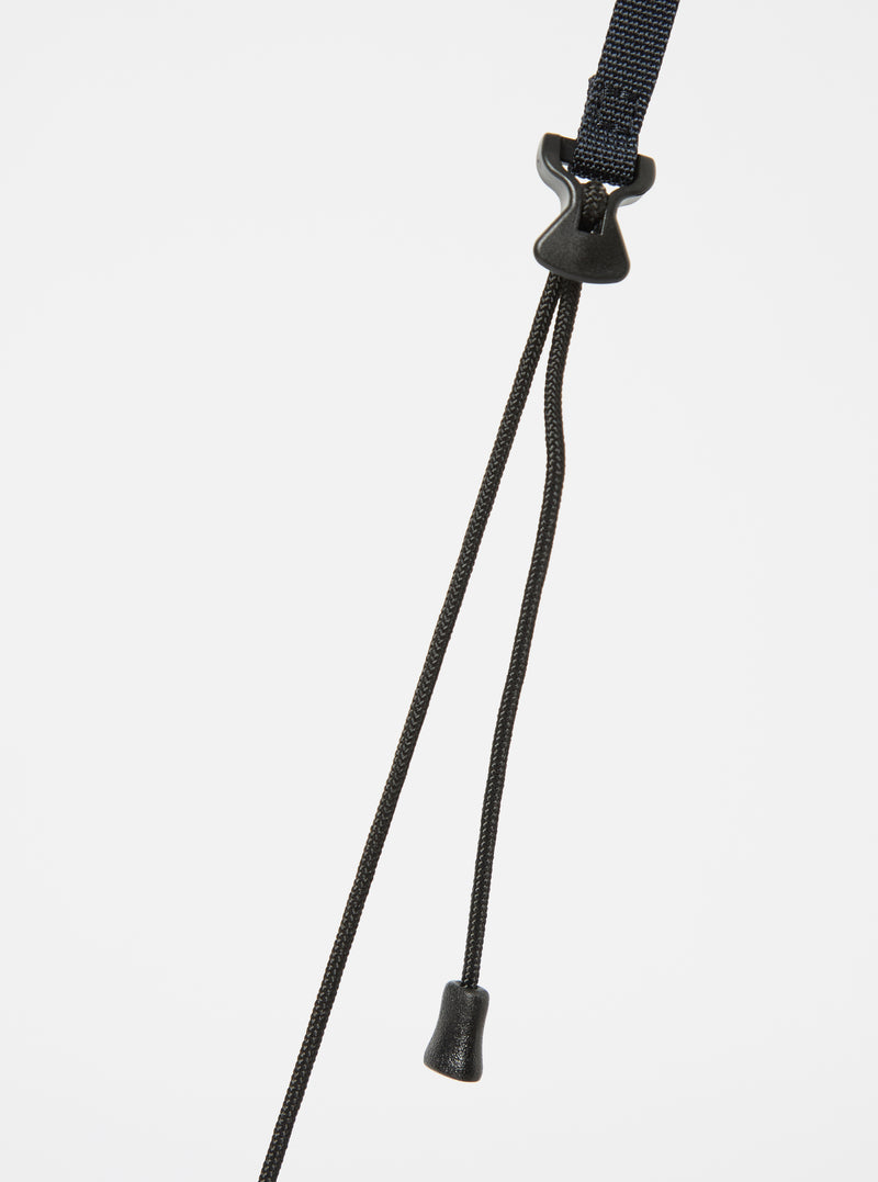 Close-up of the black strap and toggle of the master-piece x Universal Works Black Recycled Tech Canvas Sacoche against a white backdrop.