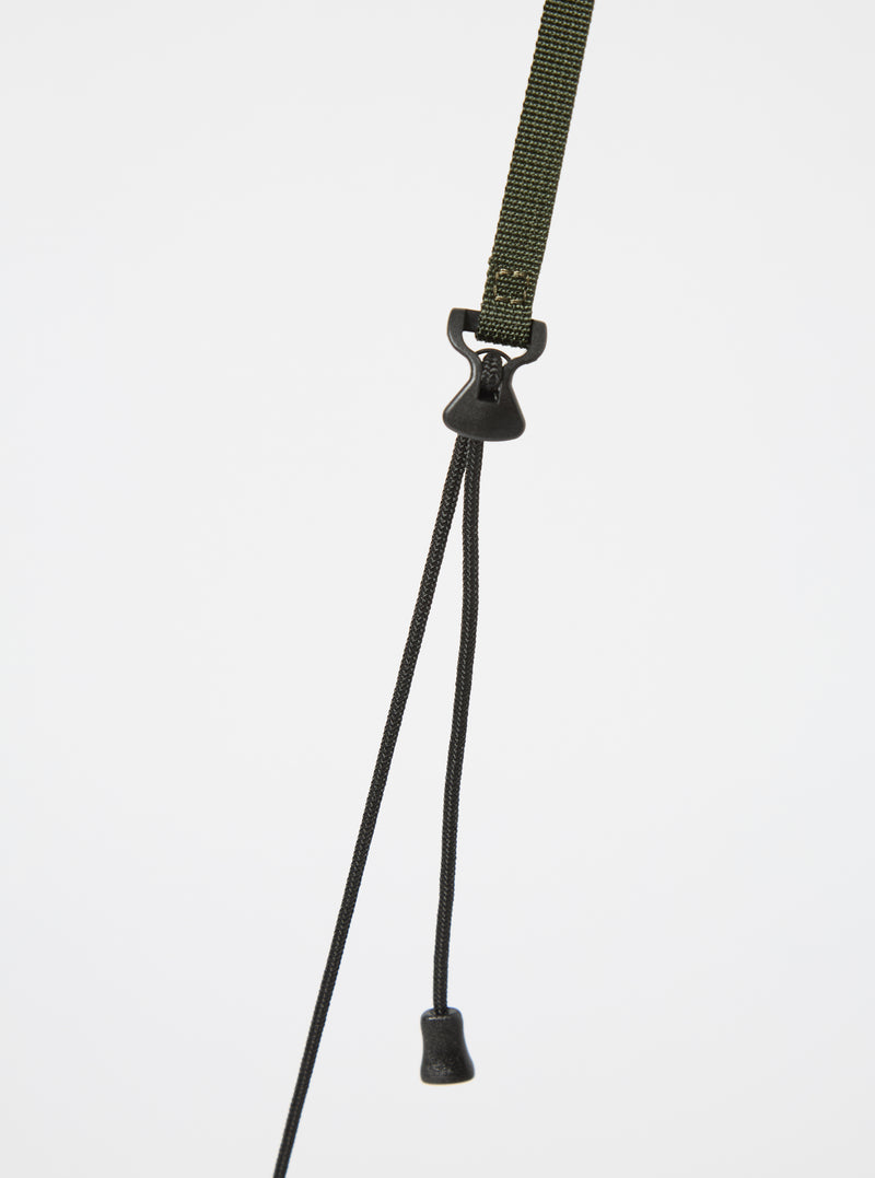 Close up of the olive strap and black drawstrings of the master-piece x Universal Works Olive Recycled Tech Canvas Sacoche against a white background.