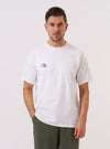 A model wears the master-piece x Universal Works White Single Jersey Print Tee against a plain white background. The T-shirt is a short-sleeved, crewneck style featuring a large circular graphic on the front with the words Master-piece and Universal Works encircling a central design. The model is shown from the waist up, and the garment has a relaxed fit. No mannequin is present in the image.