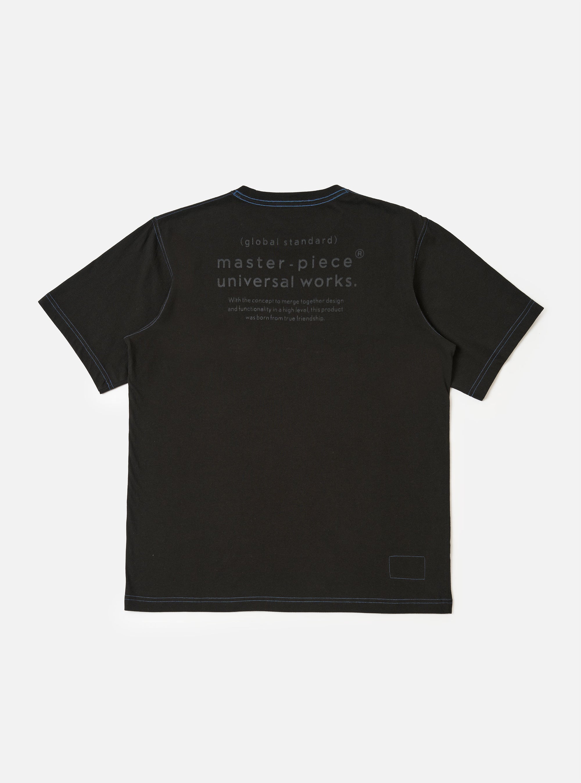 The master-piece x Universal Works Black Single Jersey Print Tee is shown from the back as a flat lay against a white background. The image highlights the short sleeves and the straight hem of the black cotton t-shirt.