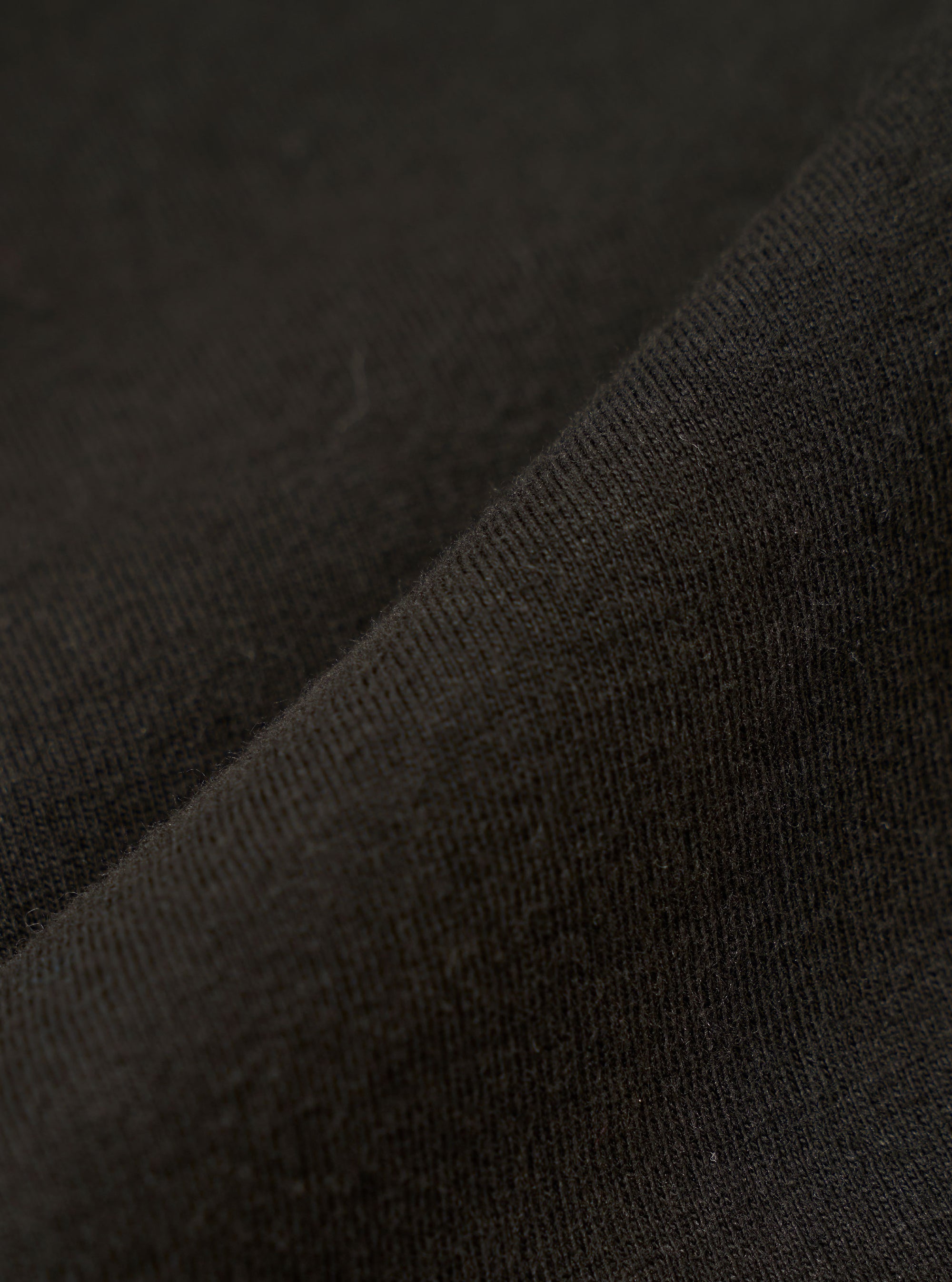 A close-up fabric swatch of the master-piece x Universal Works Black Single Jersey Print Tee highlights the solid black color and the smooth, fine-knit texture of the single jersey cotton fabric.