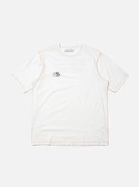 The master-piece x Universal Works White Single Jersey Print Tee is shown as a flat lay against a plain white background. This short-sleeved white t-shirt features a simple ribbed crew neckline and a relaxed fit. A small, dark graphic is printed on the left chest area, and a logo patch is visible near the front hem.