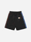 The master-piece x Universal Works Black Recycled Poly Tech Pleated Track Short is shown from the back as a flat lay against a white background. The image highlights the elasticated waistband and two rear pockets, including one with a button-down flap. The black recycled poly-tech fabric has a smooth, utilitarian finish.