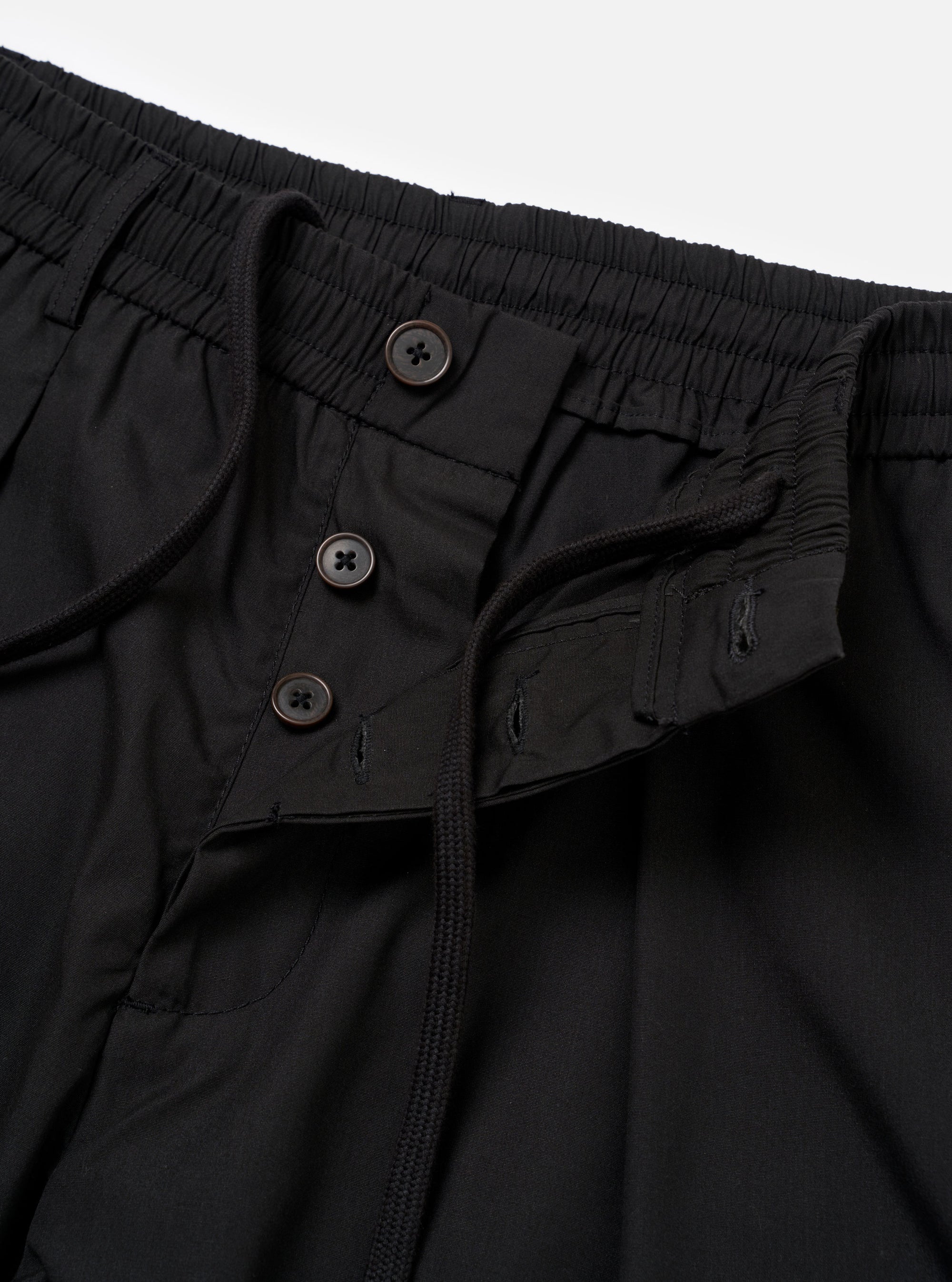 The master-piece x Universal Works Black Recycled Poly Tech Pleated Track Short is shown from the back as a flat lay against a plain white background. The image highlights the elasticated waistband with a drawstring, two rear welt pockets, and the loose fit of the shorts.