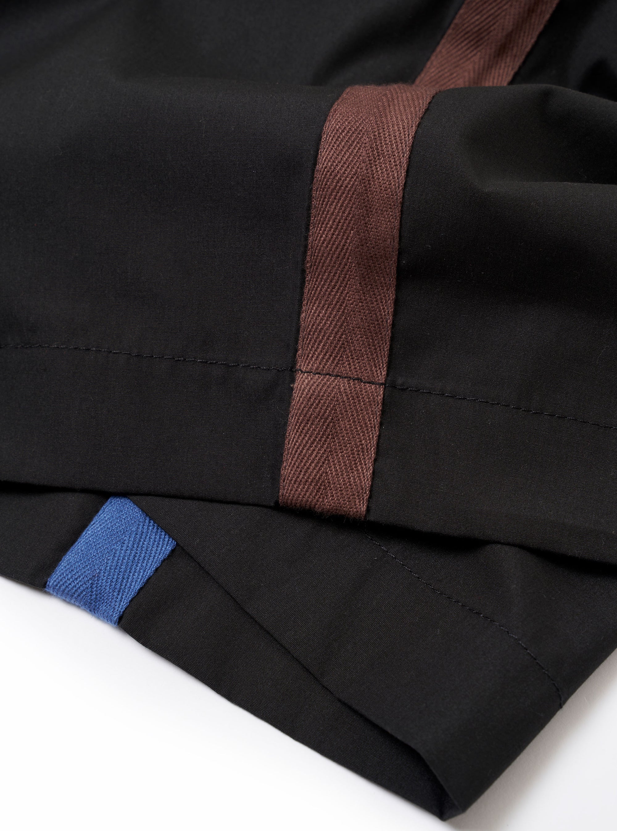 The master-piece x Universal Works Black Recycled Poly Tech Pleated Track Short is shown from a rear angle as a flat lay against a white background. The image highlights the two rear pockets, including one with a button-down flap, and the elasticated waistband with belt loops.