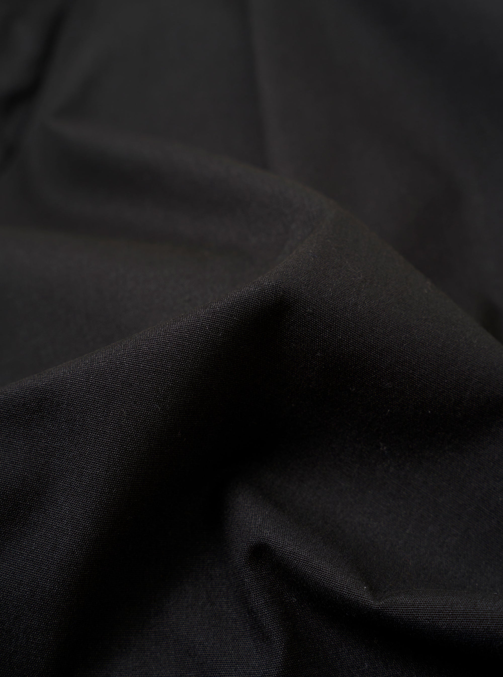 The master-piece x Universal Works Black Recycled Poly Tech Pleated Track Short is shown from the back as a flat lay against a plain white background. The image highlights the two rear pockets, the elasticated waistband with belt loops, and the loose, relaxed fit of the black fabric.