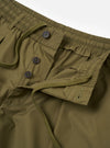 The master-piece x Universal Works Olive Recycled Poly Tech Pleated Track Short is shown from a rear angle as a flat lay against a plain white background. The image highlights the two rear pockets, one with a button-down flap, and the elasticated waistband with belt loops.