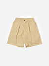 The master-piece x Universal Works Sand Recycled Poly Tech Pleated Track Short is shown as a flat lay against a plain white background. The shorts feature a relaxed, loose fit with a prominent single pleat on each leg, an elasticated waistband with a matching drawstring, and a zip fly. Two side pockets are visible. The fabric is a compact, sand-colored recycled polyester and cotton blend.