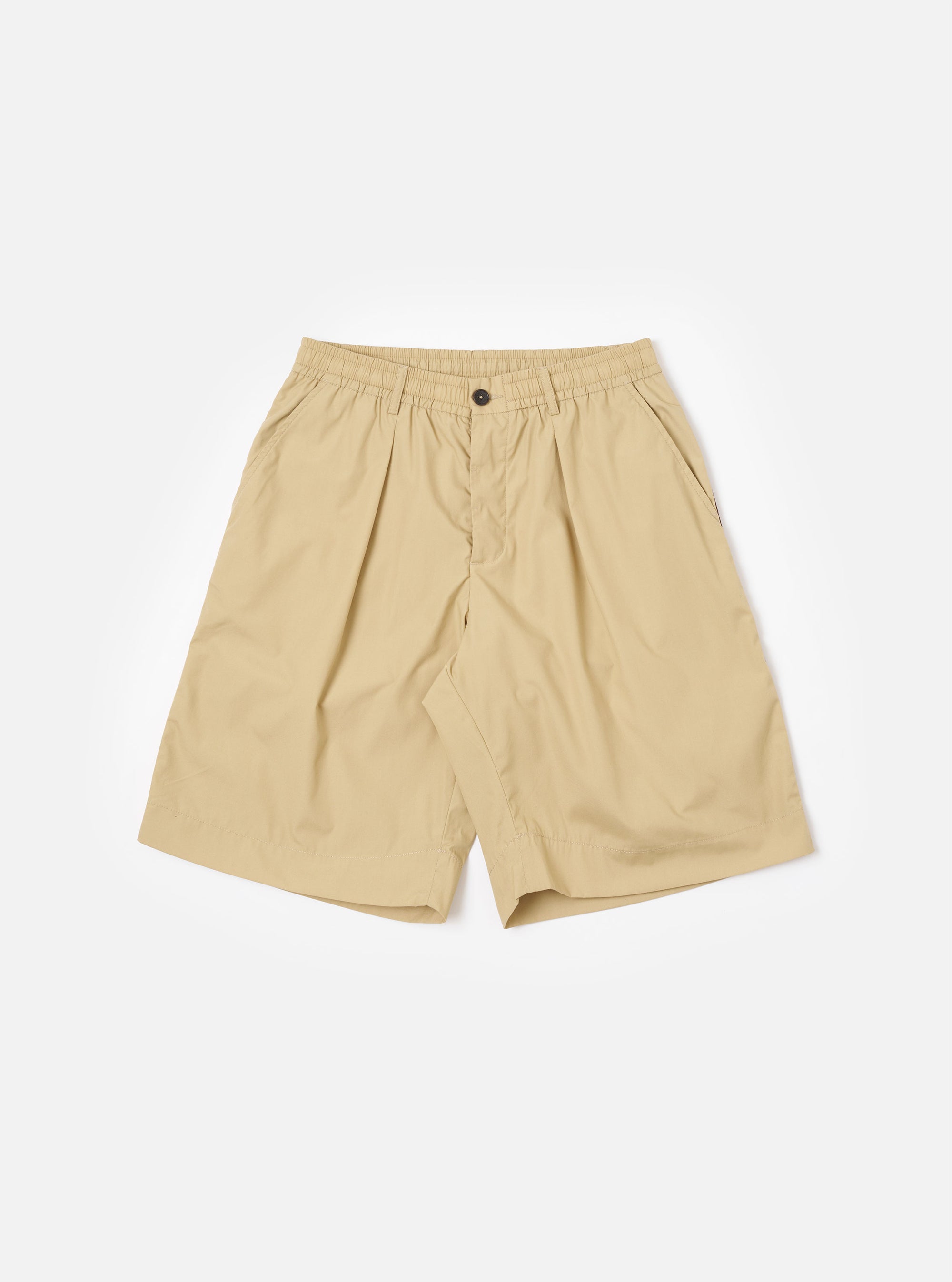The master-piece x Universal Works Sand Recycled Poly Tech Pleated Track Short is shown as a flat lay against a plain white background. The shorts feature a relaxed, loose fit with a prominent single pleat on each leg, an elasticated waistband with a matching drawstring, and a zip fly. Two side pockets are visible. The fabric is a compact, sand-colored recycled polyester and cotton blend.