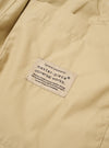 The master-piece x Universal Works Sand Recycled Poly Tech Pleated Track Short is shown from the back as a flat lay against a white background. The image highlights the two rear pockets, including one with a button-down flap, and the elasticated waistband.