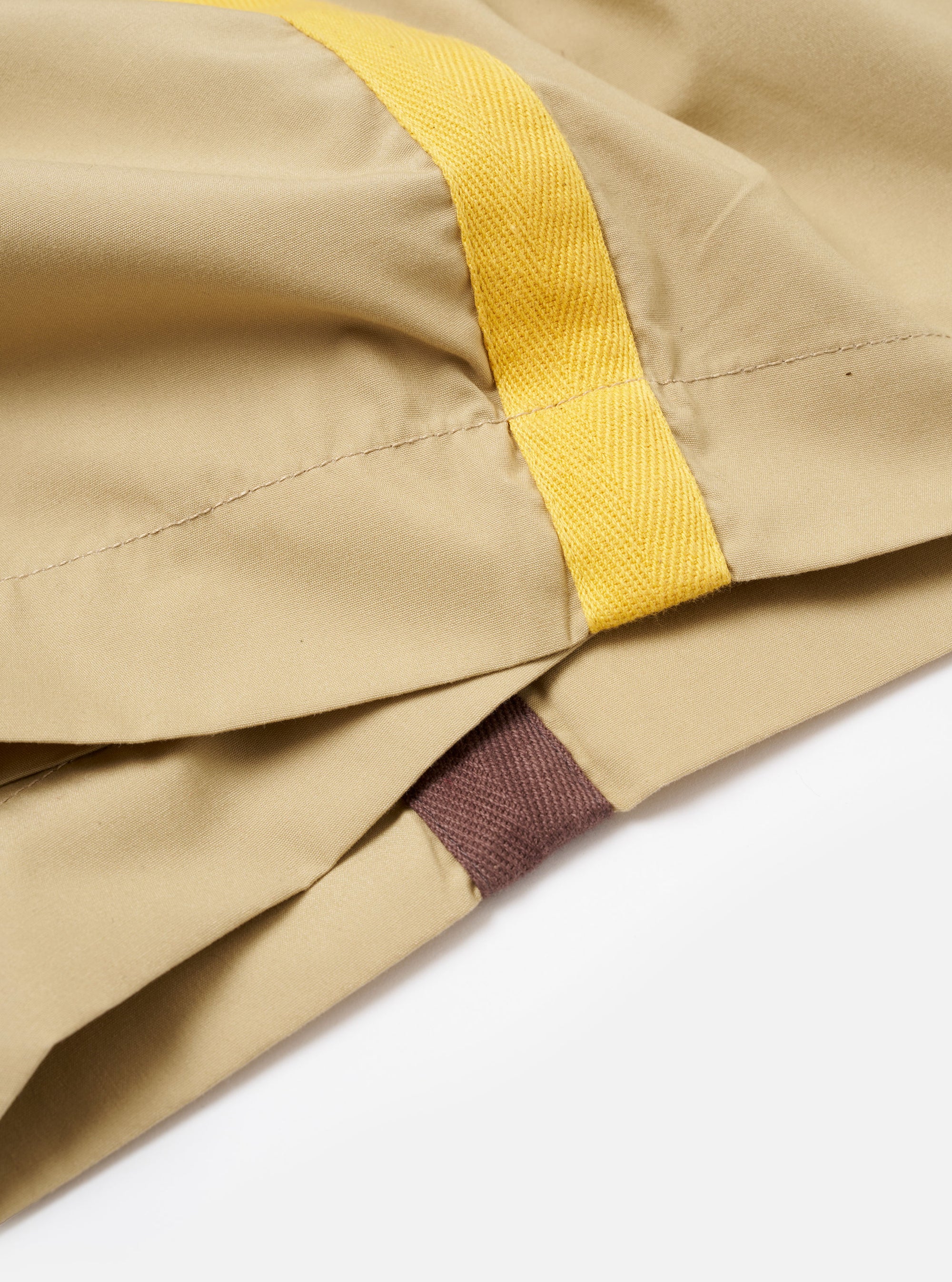 The master-piece x Universal Works Sand Recycled Poly Tech Pleated Track Short is shown from a rear angle as a flat lay against a plain white background. The image highlights the back of the shorts, featuring a visible elasticated waistband and two rear pockets, with the right pocket including a button-flap closure.