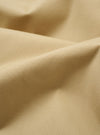 The master-piece x Universal Works Sand Recycled Poly Tech Pleated Track Short is displayed in a detail view as a flat lay against a white background. This close-up highlights the interior waistband, featuring a white collaboration label and a tan adjustable cotton drawstring. The sand-colored fabric has a clean, utilitarian appearance with visible stitching along the elasticated waist.