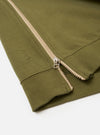 The master-piece x Universal Works Olive Brush Back Sweat S/S Billy Sweat is shown from the back as a flat lay against a plain white background. The short-sleeved sweatshirt features a ribbed crew neck, a straight hem, and a small collaborative brand patch near the bottom left side.