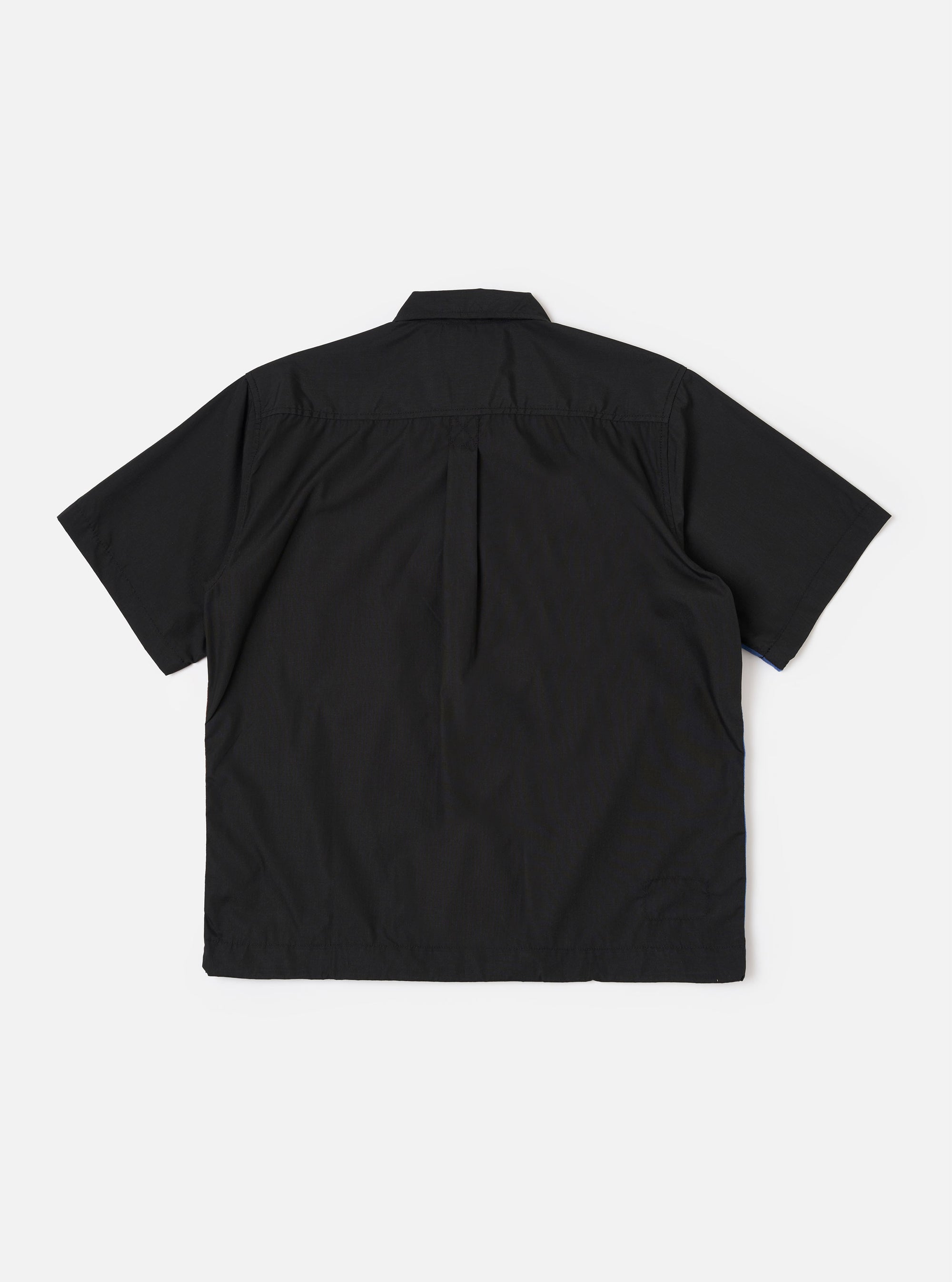 The master-piece x Universal Works Black Recycled Poly Tech Tech Overshirt is shown from the back as a flat lay against a plain white background. The garment features a clean, structured design with a back yoke and a central box pleat. The image highlights the adjustable hem with an elasticated drawcord and the smooth finish of the black recycled polytech fabric.