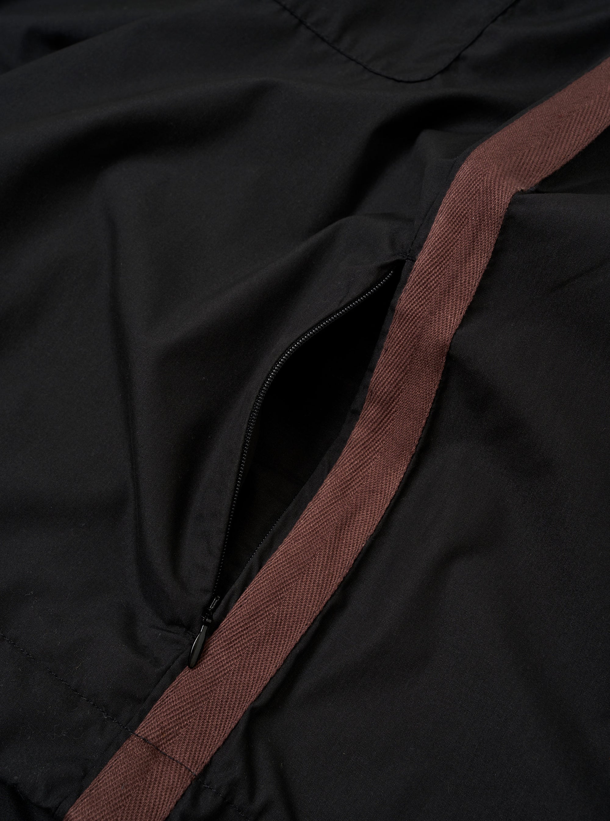 The master-piece x Universal Works Black Recycled Poly Tech Tech Overshirt is shown from the back as a flat lay against a plain white background. The image highlights the back yoke with a central box pleat and the adjustable elasticated drawcord at the hem.