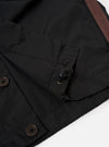 The master-piece x Universal Works Black Recycled Poly Tech Tech Overshirt is shown from the back as a flat lay against a plain white background. The image highlights the clean construction of the garment's rear, including a back yoke with a central box pleat and a straight hem. The black recycled polytech fabric has a smooth, technical finish.