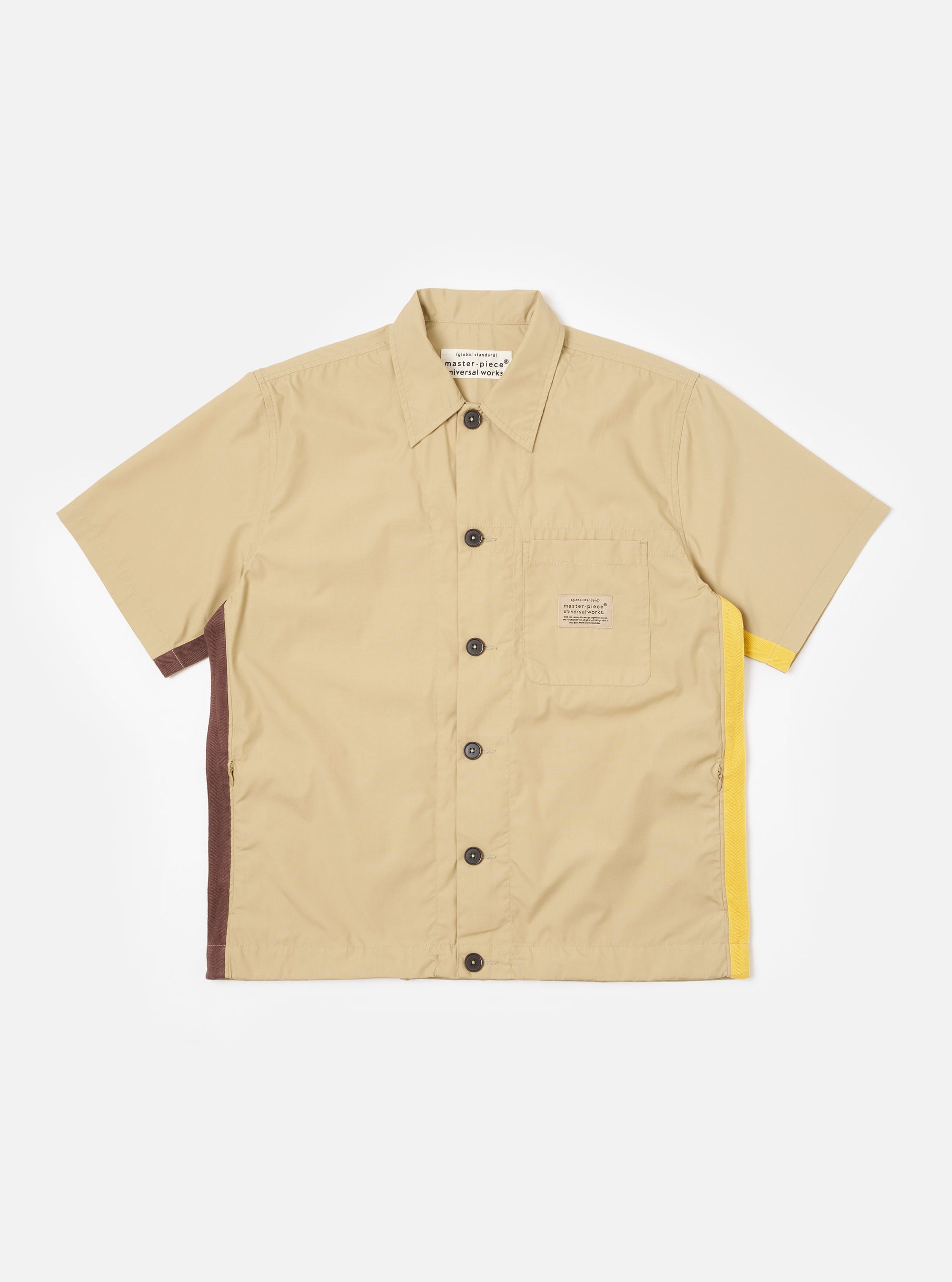The master-piece x Universal Works Sand Recycled Poly Tech Tech Overshirt is shown as a flat lay against a plain white background. The short-sleeve overshirt features a one-piece collar, a central button-down closure, and a single reinforced patch pocket on the left chest. The sand-colored recycled polytech fabric has a smooth, technical finish.