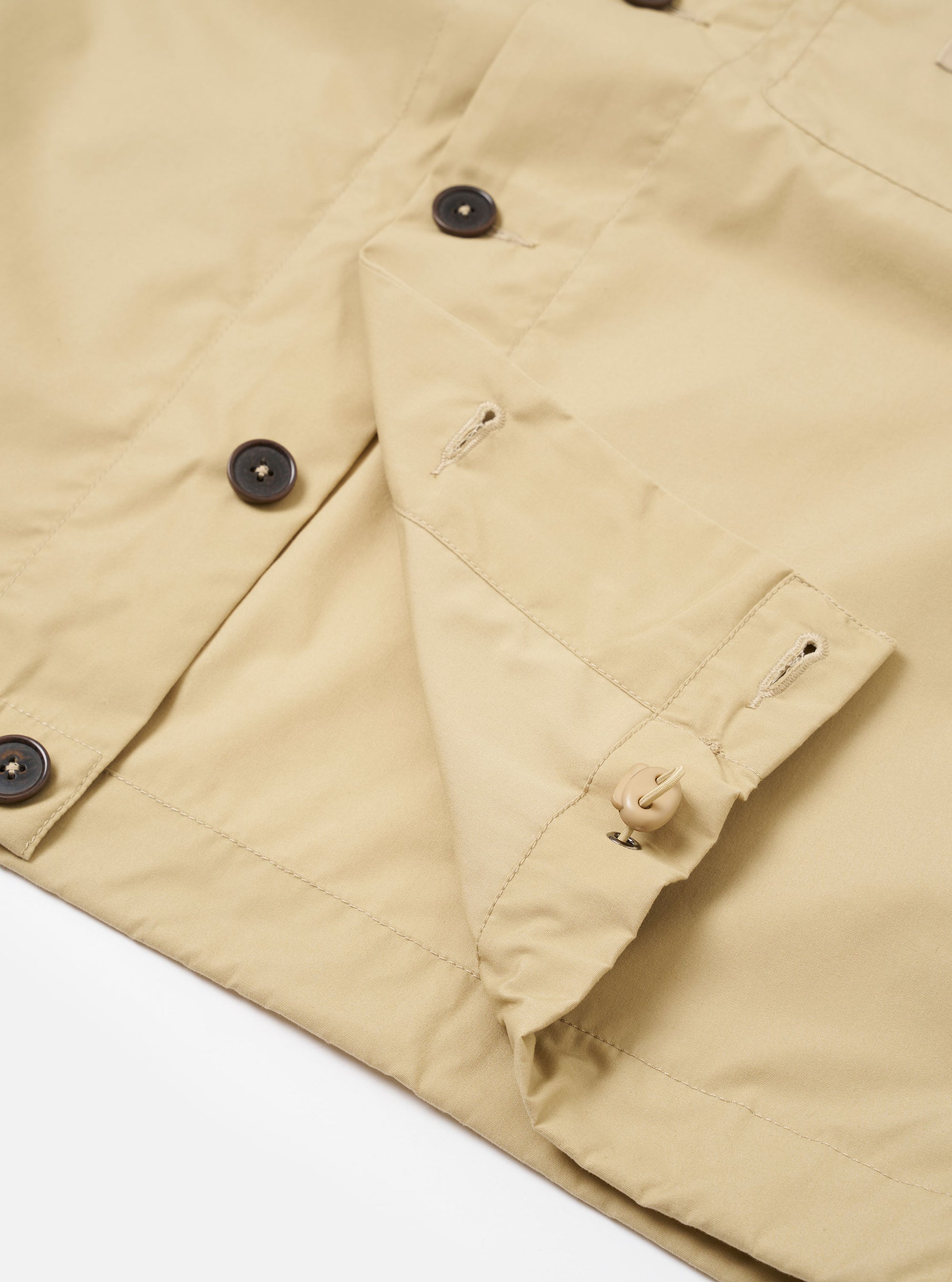 The master-piece x Universal Works Sand Recycled Poly Tech Tech Overshirt is shown from the back as a flat lay against a plain white background. The image highlights the back yoke with a central box pleat and the adjustable elasticated drawcord at the straight hem. The sand-colored recycled polytech fabric has a smooth, technical appearance.