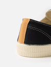 Close-up of the Novesta for Universal Works Black Canvas Star Master shoe. Features black canvas, tan accent, and a textured white sole on a clean white background.