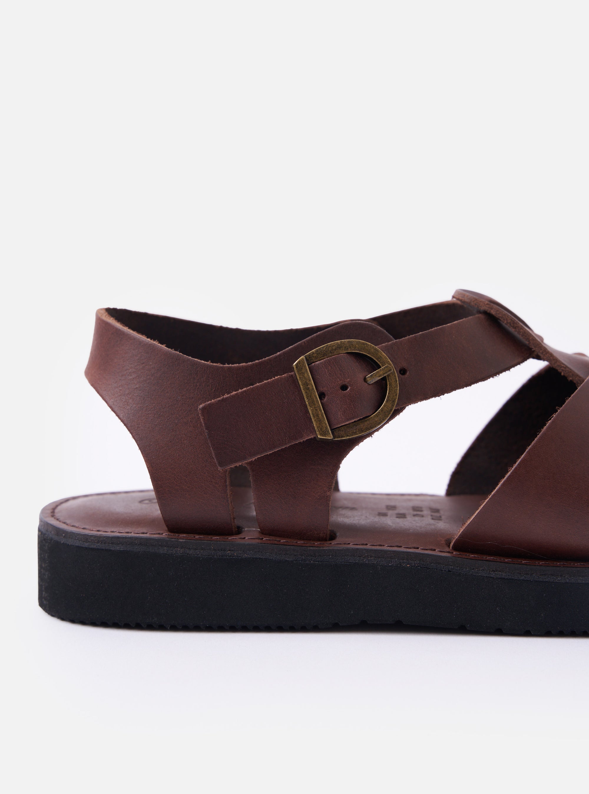 The Organic Handloom Dark Brown Leather Gurkha is shown from a rear angle as a flat lay against a plain white background. The image highlights the closed heel counter and the adjustable ankle strap with a silver-tone metal buckle. The dark brown oil leather has a smooth, slightly glossy finish, and the thick, lightweight black foam rubber sole is visible at the base.