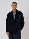 A model poses in front of a white backdrop, wearing the Navy Velveteen Manor Jacket. The jacket is a rich navy color and has a double-breasted fit.