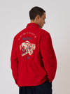 A man stands against a white backdrop, modeling the back of the Embroidered Red Mowbray Military Fatigue Jacket. The jacket features an embroidered design.