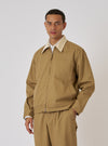 A model poses in the Khaki Works Twill Rose Bowl Jacket. The jacket is khaki with a tan collar. The background is a plain white studio backdrop.