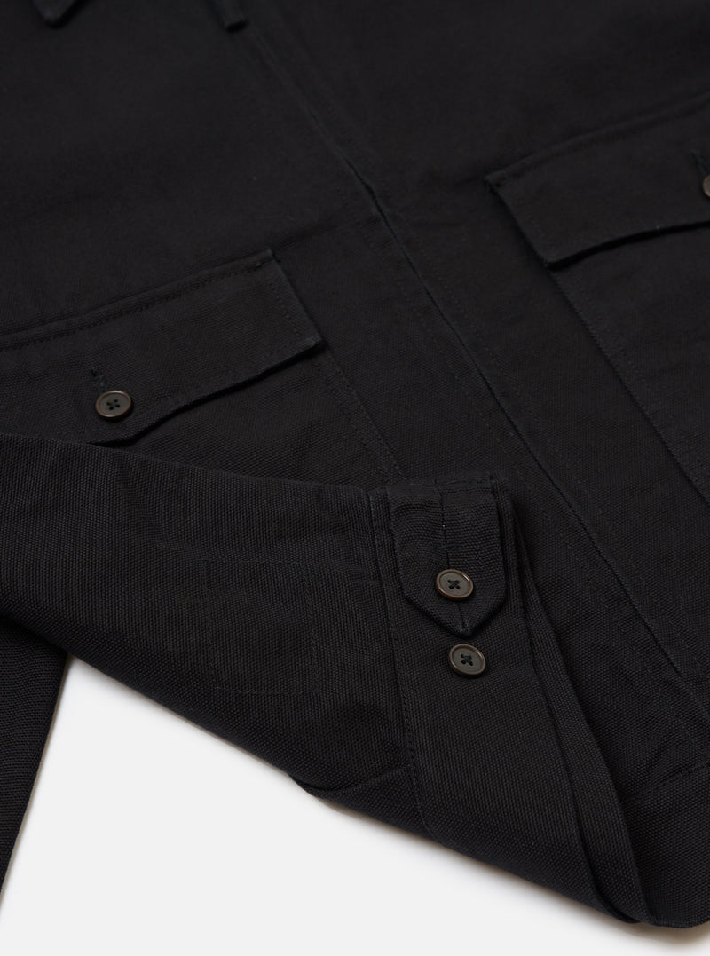 Close-up of the Black Organic Canvas S130 Jacket on a white surface. The jacket features a button-up design and visible pockets, showcasing its organic canvas material.