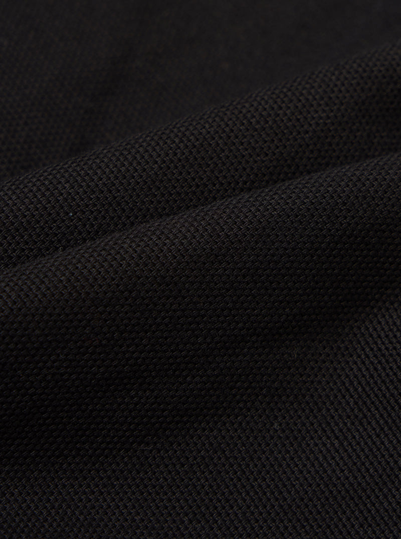 Close-up of the Black Organic Canvas S130 Jacket, showcasing the texture and weave of the material. The fabric is draped to highlight its quality.