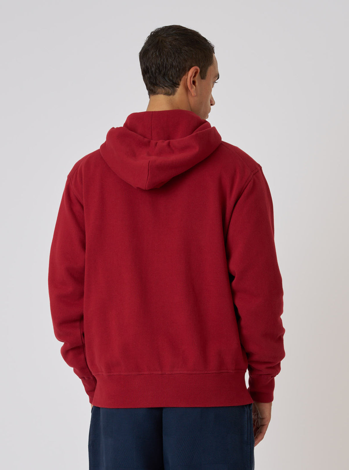 Back view of a man wearing the Red Brush Back Sweat New York Hoody. The red cotton hoody is set against a plain white background.