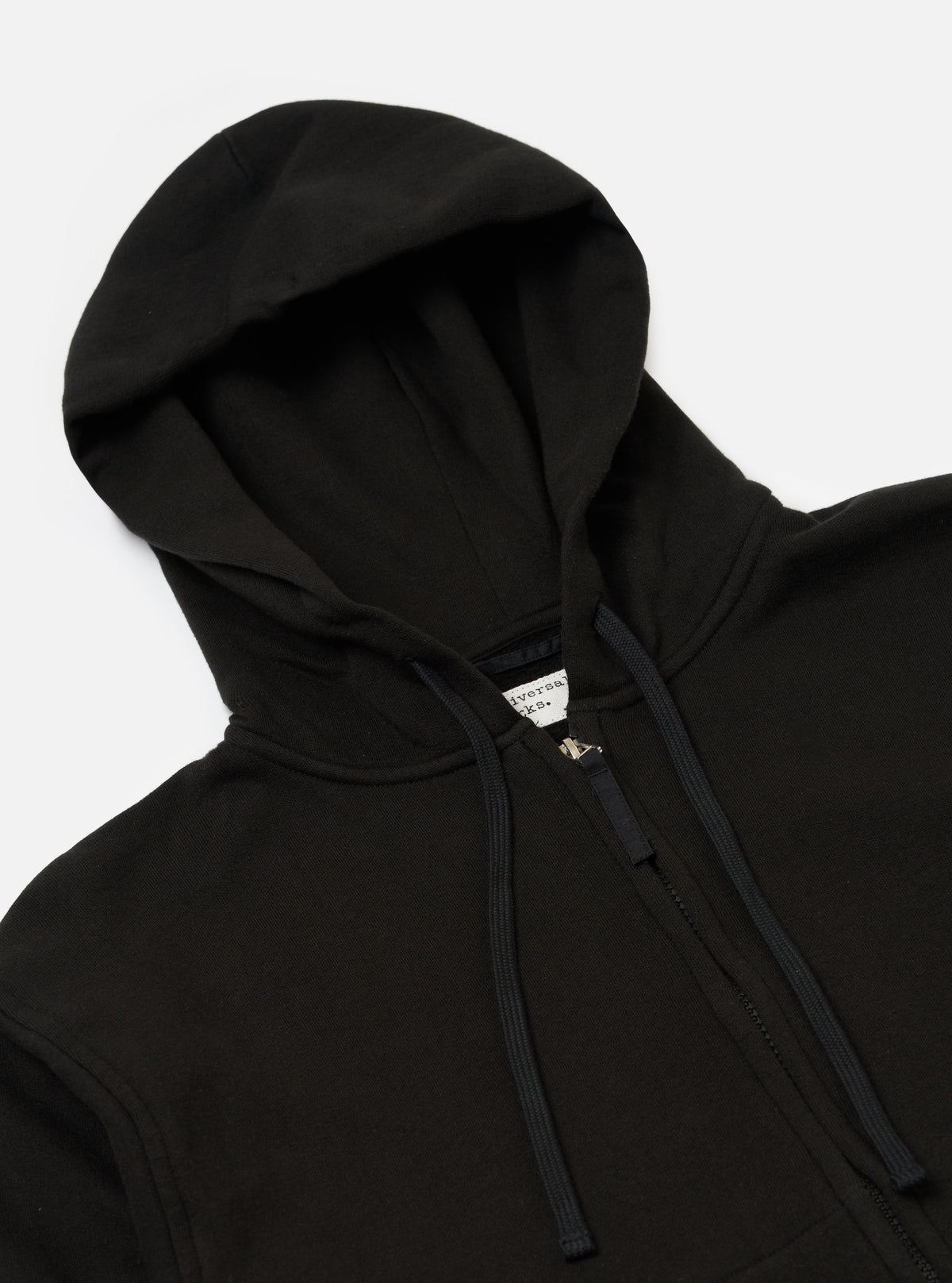 Close-up of the Black Brush Back Sweat New York Hoody on a white background. The black zip-up hoody has a drawstring and a visible tag.