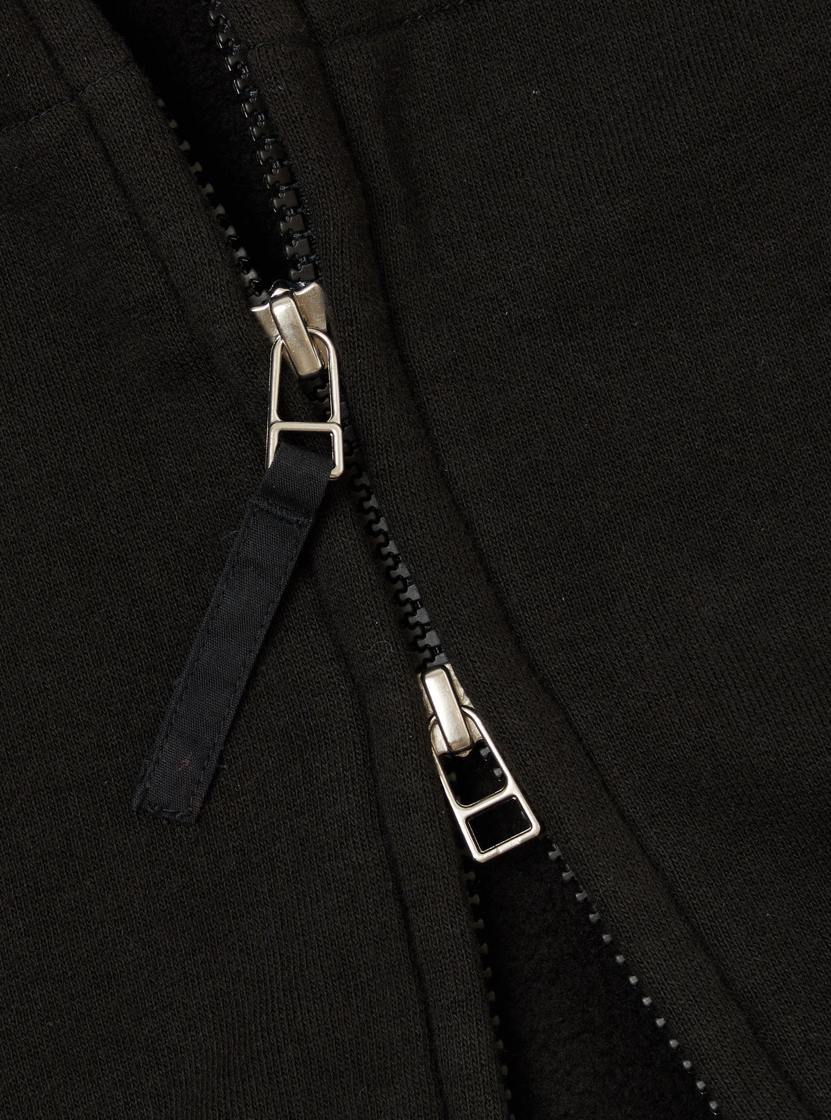 Close-up of the zipper on a Black Brush Back Sweat New York Hoody. The black fabric and silver zipper are detailed in this shot.