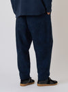 Back view of a model wearing the Black/Indigo Denim Camo Braga Pant. The pants are loose-fitting and paired with black shoes, set against a plain background.