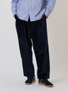 A model stands against a white backdrop wearing the Navy Velveteen Oxford Pant. The pants are paired with a light blue button-down shirt and black sneakers.
