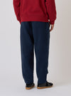 Back view of a model wearing a red sweatshirt and Dark Navy Patchwork Weave Cotton Pleated Track Pant. The pants have a subtle patchwork pattern. Shot against a plain white backdrop.