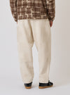 Back view of a model wearing Ecru Patchwork Weave Cotton Pleated Track Pant. The pants have a subtle patchwork pattern. Shot in a studio with a plain white background.
