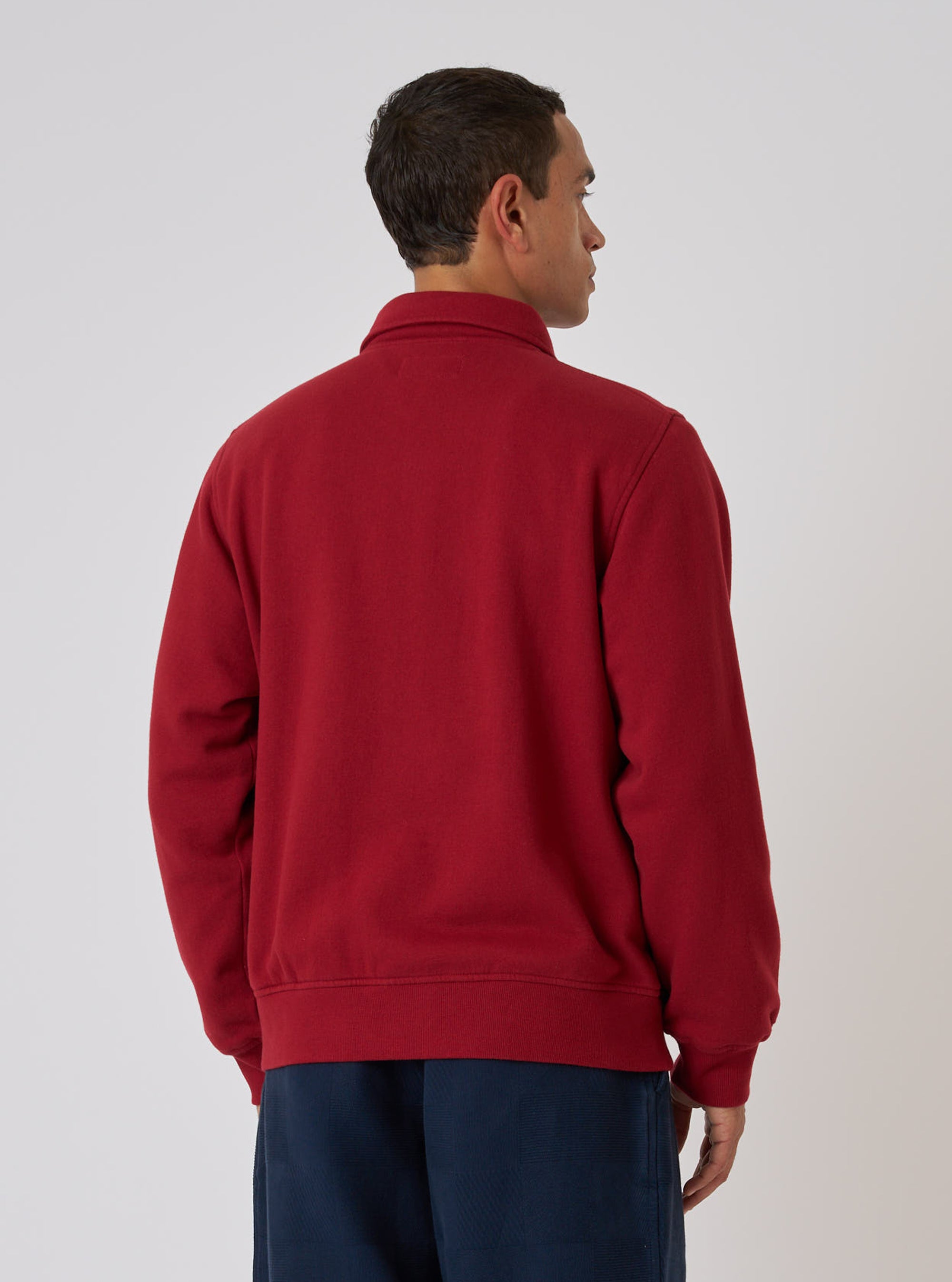 Back view of a model wearing a red Brush Back Sweat Tyler Sweat Jacket. The jacket is cotton. The background is a plain studio backdrop.