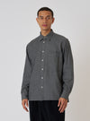 A model poses in a Charcoal Brushed Organic Cotton Square Pocket Shirt against a white backdrop. The shirt is a charcoal color and has a square pocket.